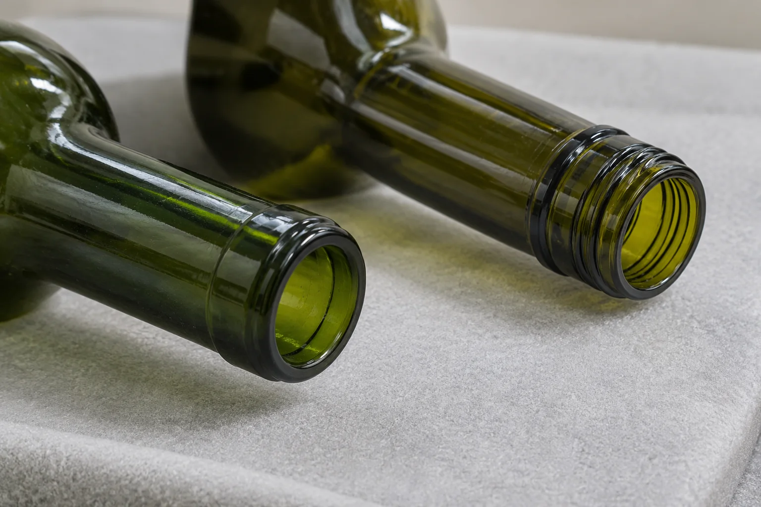 Close-up of an open smooth-lipped green bottle neck beside a bottle neck with external screw threads
