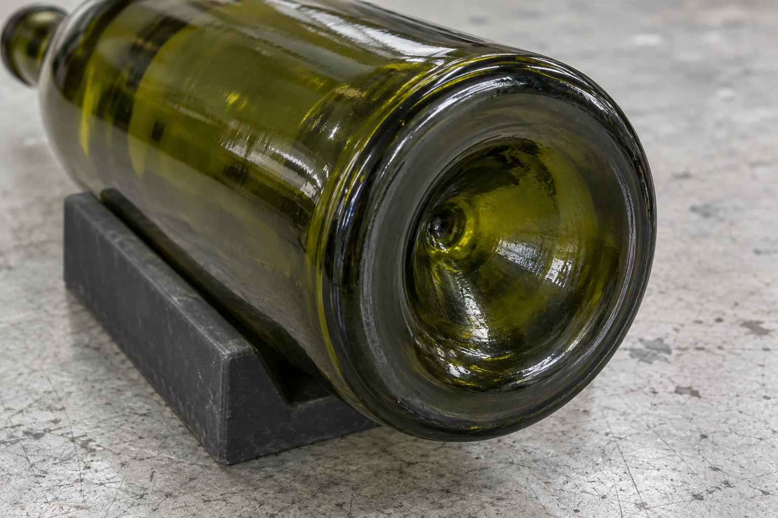 Concave punt and circular bearing ring on the bottom of a green wine bottle supported in a cradle